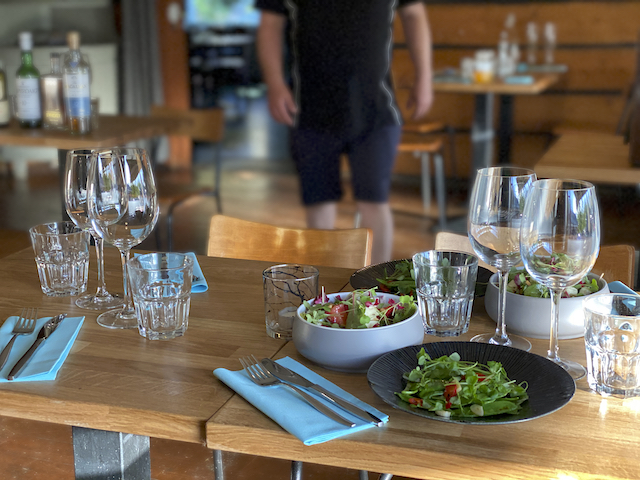 A restaurant table set with glasses, salads and cutlery.
