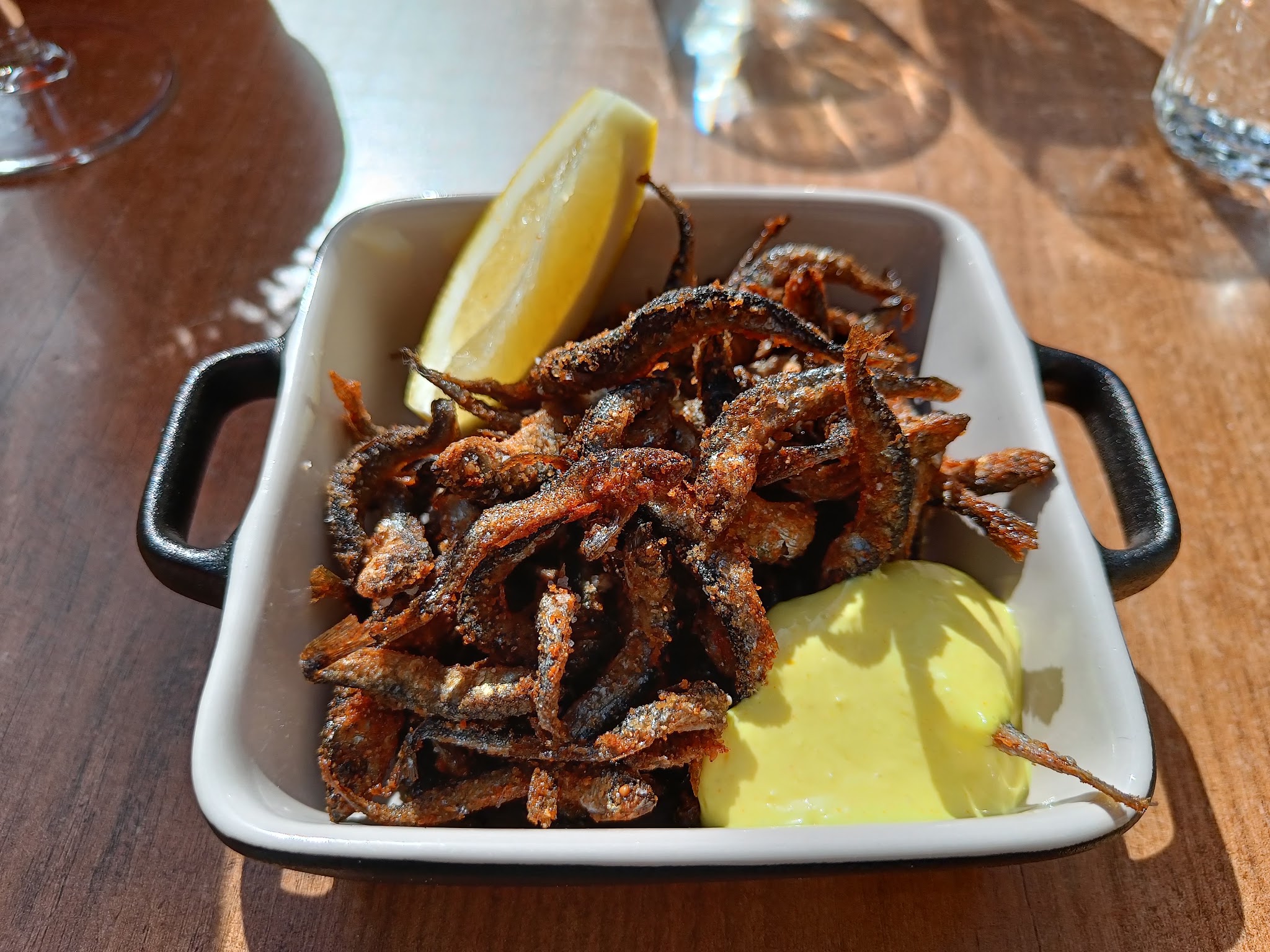 Fried food with lemon and dip on a wooden table.